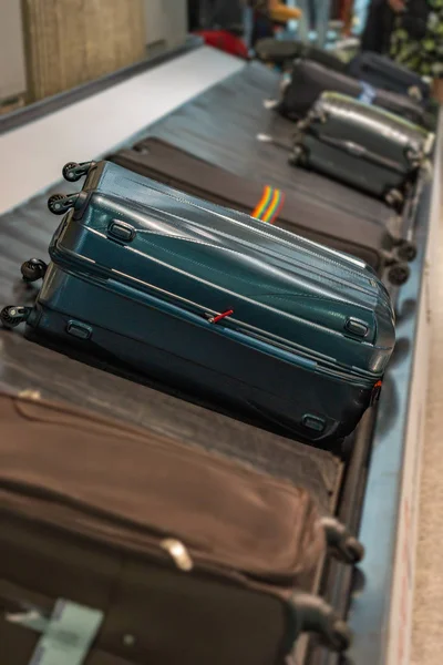 Suitcases on luggage conveyor belt at arrival terminal in airport