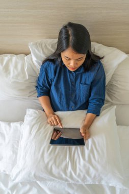 Yatakta dijital tablet kullanan kadının yüksek açılı görüntüsü