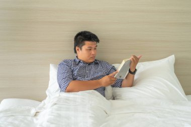 İş adamı yatmadan önce kitap okuyarak rahatlıyor.