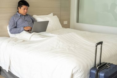 Genç iş adamı iş gezisinde dizüstü bilgisayar kullanıyor.