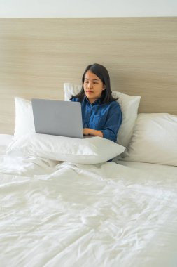 Evde dizüstü bilgisayarla çalışan bir kadın yatak odasında yatıyor.