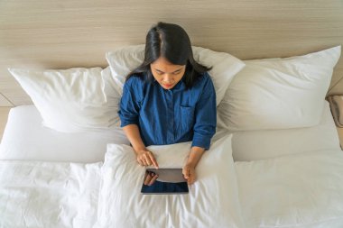 Yatakta tablet kullanan kadının yüksek açılı görüntüsü