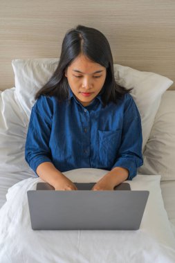 Otel odasında dizüstü bilgisayarda yazan kadının yüksek açılı görüntüsü