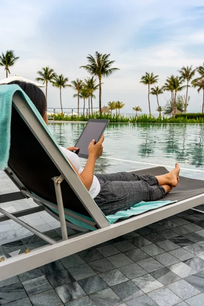 Jonge vrouw met behulp van digitale tablet bij mooi infinity zwembad — Stockfoto