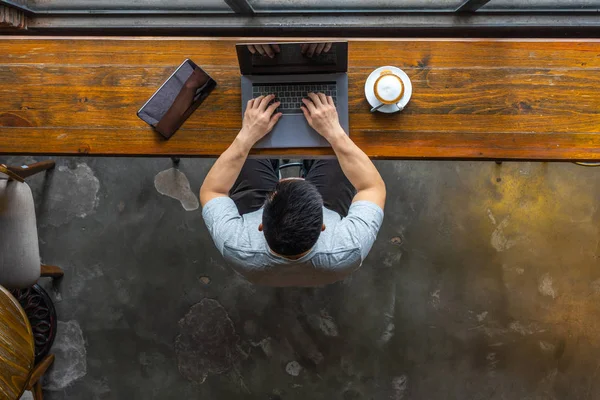 Aislado joven freelancer asiático utilizando ordenador portátil en rústico coffeeshop — Foto de Stock