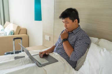 otel odasında dizüstü bilgisayar üzerinde çalışan genç işadamı