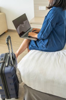 Yatakta otururken dizüstü bilgisayar kullanan bir kadın.