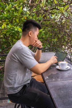 Genç serbest çalışan, güzel kahve dükkanında kapuçino içerken tablet kullanıyor.