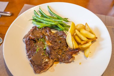 Pepper sauce beef steak with roasted potatoes and string beans