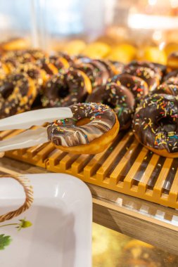 Customer hand buying chocolate donut at pastry shop