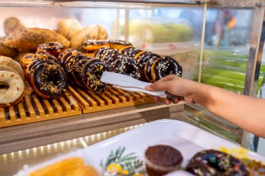 Human hand picking a delicious chocolate donut by clamp