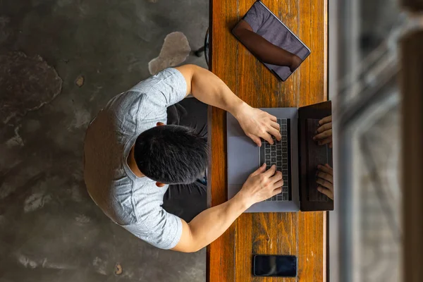 Joven hombre escribiendo portátil junto a la tableta digital y el teléfono celular — Foto de Stock