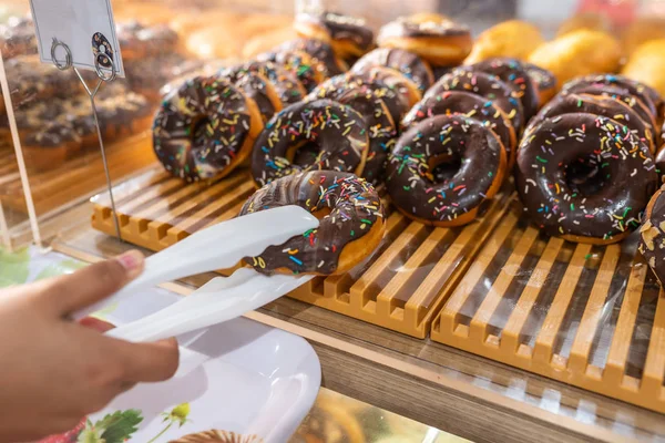 Handklem plukken bevroren chocoladedonut in de banketbakkerij — Stockfoto