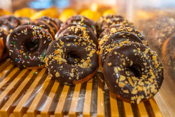 Heerlijke matte chocolade donuts met sprinkle topping op het dienblad — Stockfoto