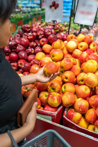 Ασιάτισσα που μαζεύει ένα τέλειο μήλο στο μαγαζί με τα φρούτα — Φωτογραφία Αρχείου