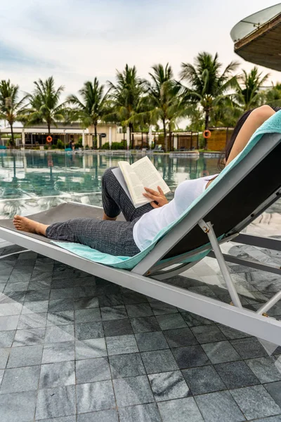 Mulher asiática lendo um bom livro na piscina de férias — Fotografia de Stock