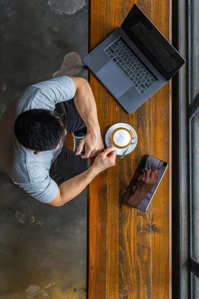 Foto vertical del freelancer musculoso usando laptop y bebiendo café — Foto de Stock