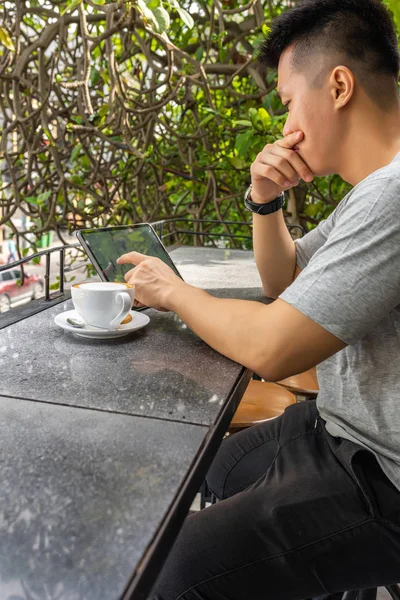 Foto de vista lateral del freelancer asiático usando tableta en coffeeshop al aire libre — Foto de Stock