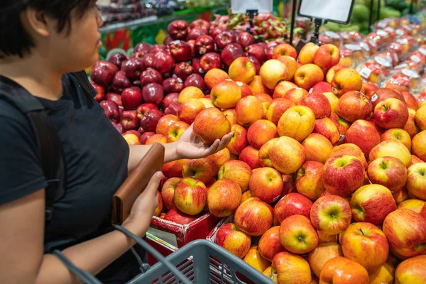 Азиатка собирает яблоки в продуктовом магазине — стоковое фото