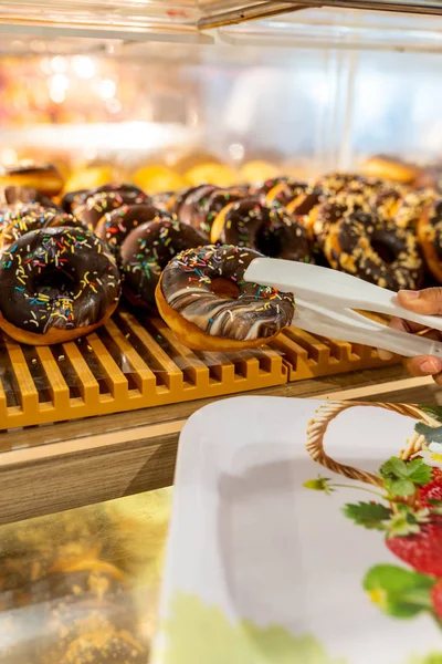 Verticale foto van menselijke hand plukken donut in banketbakkerij — Stockfoto