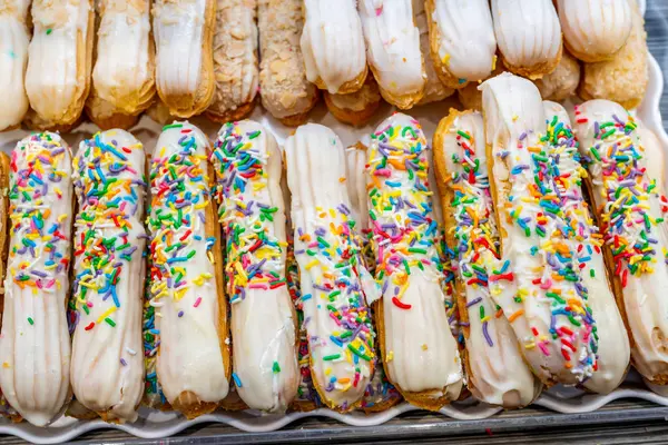 Sejumlah besar kue puff krim dan berwarna-warni di toko roti — Stok Foto