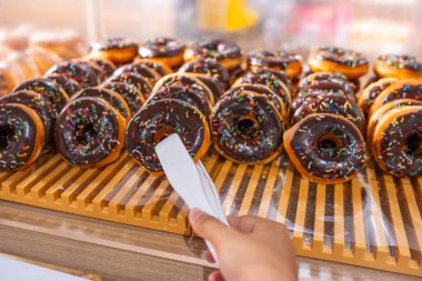 İnsan eli pastanede çikolatalı donut topluyor.