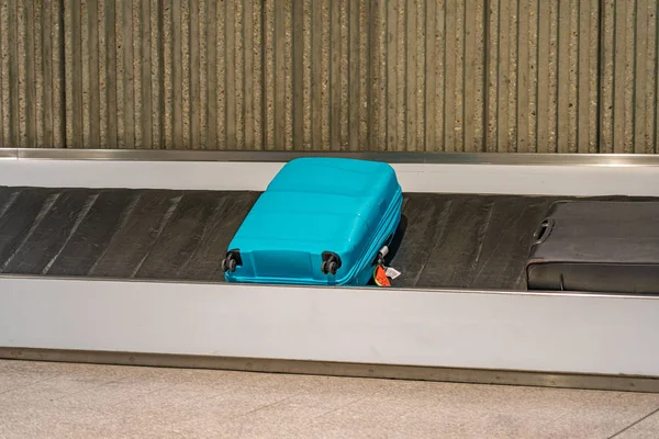 Valigia blu posa su nastro trasportatore bagagli in aeroporto — Foto Stock