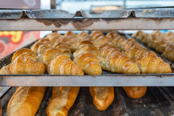 Croissant fresco y pan en el estante de enfriamiento en la fábrica de pasteles — Foto de Stock