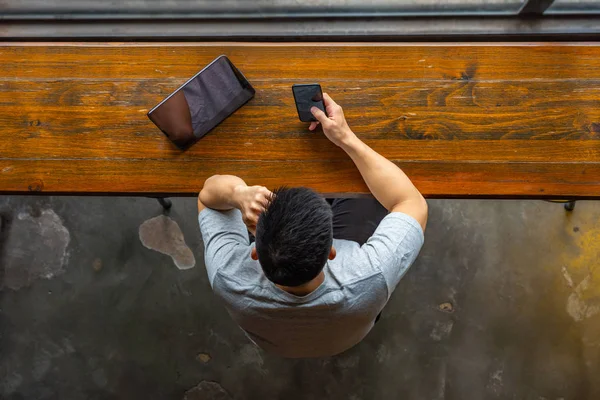 Vista de ángulo alto del hombre asiático utilizando el teléfono celular y la tableta — Foto de Stock