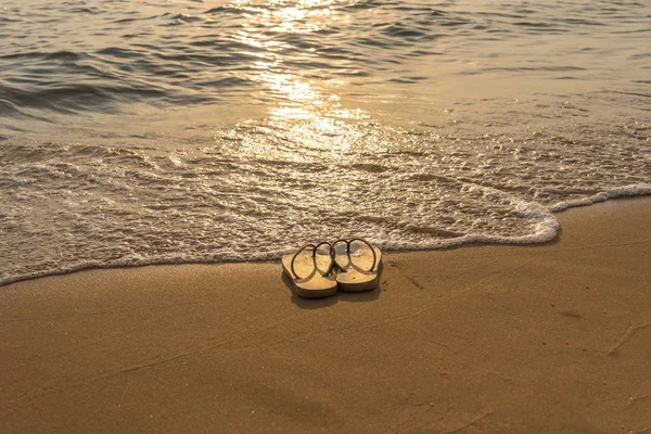 Hausschuh am ruhigen Strand im Sonnenuntergang — Stockfoto