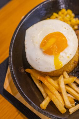 Güneşli yumurta ve patates kızartmasının cızırdayan tabakta yakın plan fotoğrafı.