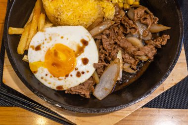 Lezzetli biftek pilavı ve demir tepside güneşli yumurta.