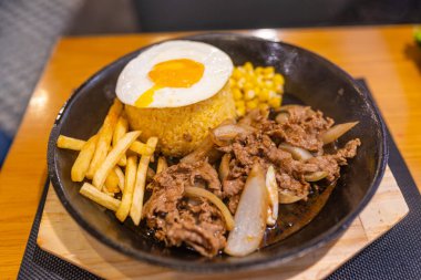 Cızırdayan demir tabakta besin değeri yüksek biftek pilavı.