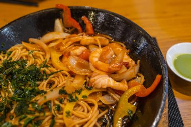 Makarnayla servis edilen kızarmış karides ve soğan.