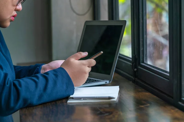 Asiatisk student som använder mobiltelefon och bärbar dator framför fönstret — Stockfoto
