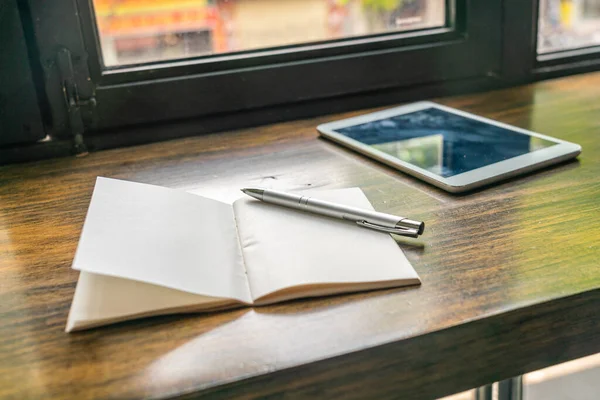 窗边木制桌子上的纸本笔记本和平板电脑 — 图库照片