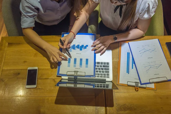 Geschäftsfrauen lesen Umsatzbericht und arbeiten spät — Stockfoto