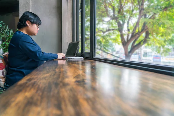 Asiática estudiante usando portátil en hermosa vista al jardín coffeeshop — Foto de Stock