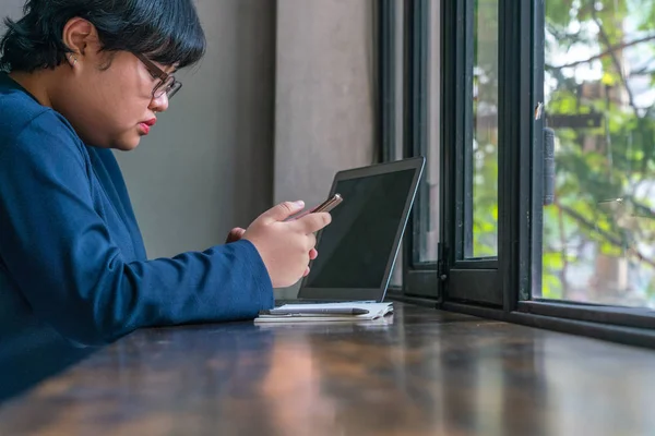 Asiática taquigrafía mujer usando celular mientras sentado por la ventana — Foto de Stock