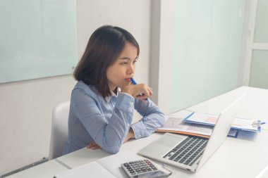 Genç Asyalı iş kadını düşünüyor, kalemle dudaklarına dokunuyor.