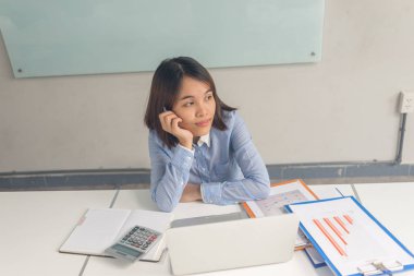 Genç Asyalı ofis kadını iş yerinde düşünüyor ve çalışıyor.