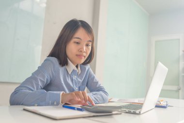 İş için hesap makinesi kullanan genç Asyalı iş kadını