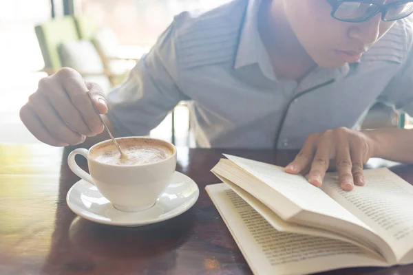 Een hand roer koffie en een hand boek geopend — Stockfoto