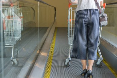 Yüksek topuklu bir kadın alışveriş arabası kullanıyor.