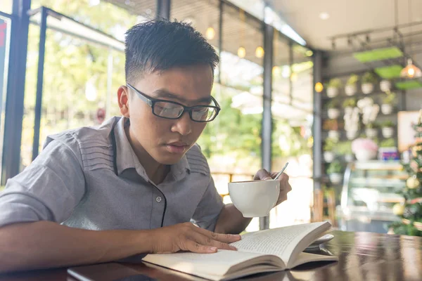 Homem asiático bebendo café e lendo livros — Fotografia de Stock