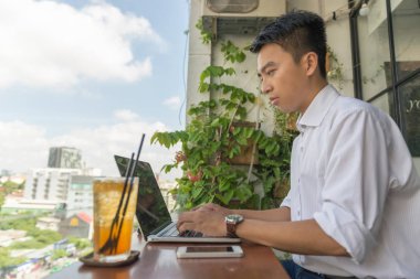 Dışarıda dizüstü bilgisayarda çalışan Asyalı serbest yazar.