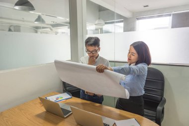 Genç Asyalı yönetici çalışanların raporlarını okuyor