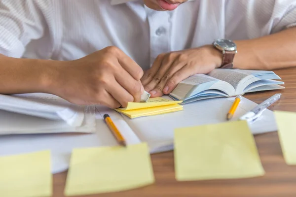 Mano humana borrando algunas palabras en nota adhesiva — Foto de Stock