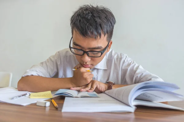 Ung asiatisk student somnar när han gör hemarbete — Stockfoto