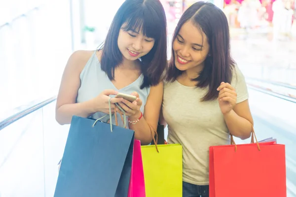 Shopaholic girl holding shopping bag, using smartphone — 스톡 사진
